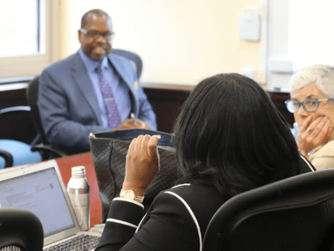 faculty members sit together at a table to in discussion