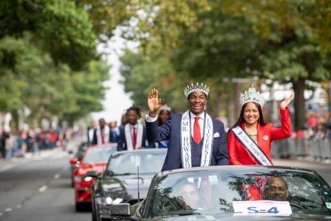 Mr and Miss Howard 2019 waving at crowd while riding in car during Homecoming parade