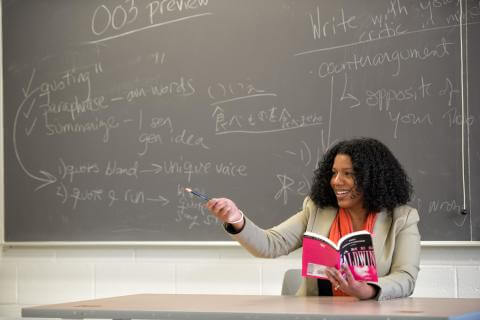 Professor responding to student with book in hand