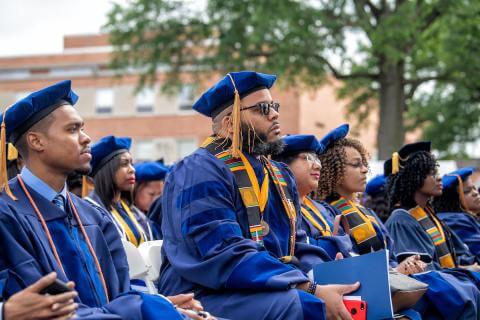 Graduates sit outdoors during commencement ceremony 