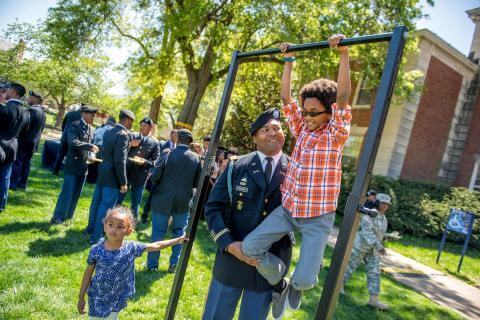 ROTC Army member watching kids play on monkey bars